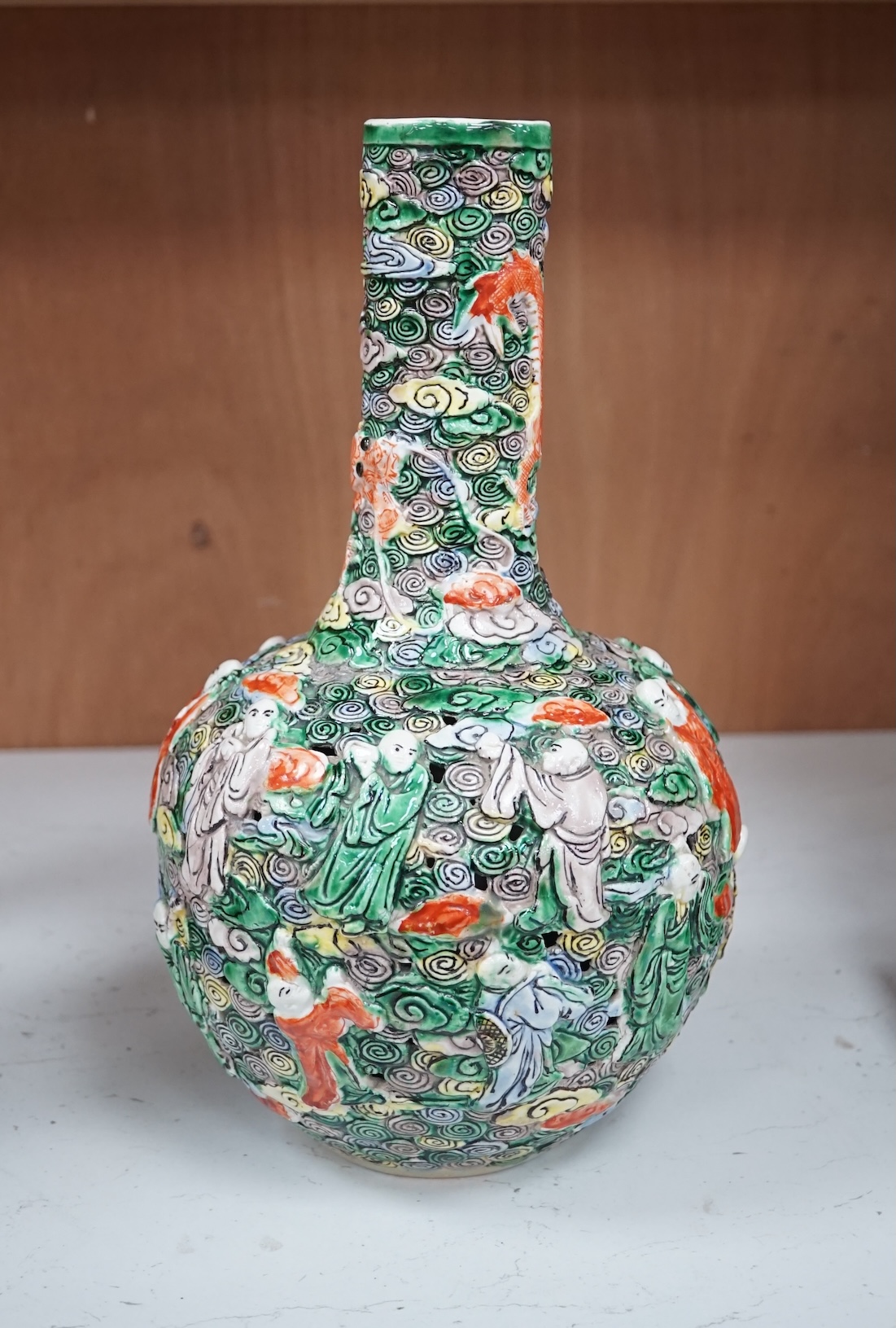 A Chinese moulded and reticulated porcelain eighteen luohan bottle vase, early 20th century, 34cm high. Condition - good